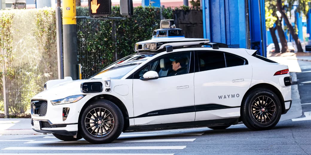 A Waymo self-driving test vehicle equipped with roof-mounted sensors.