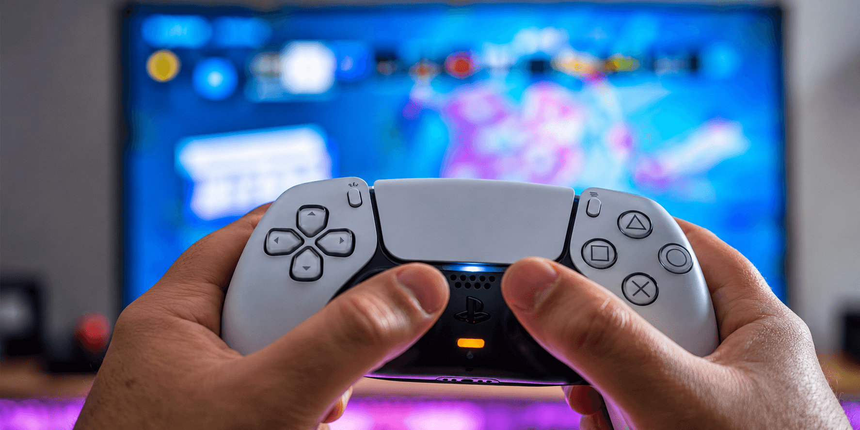 A player holding a PlayStation DualSense controller in front of a television.