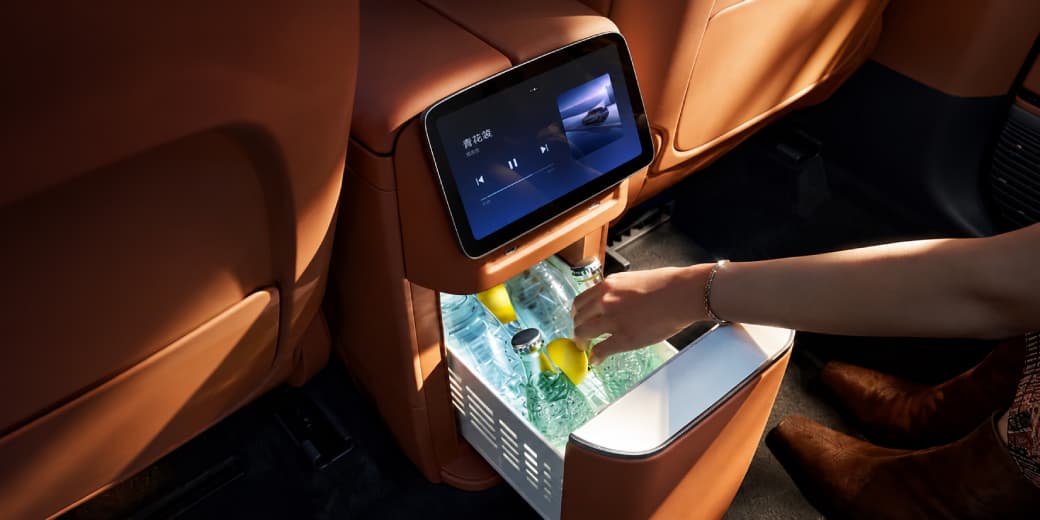 Open Xpeng G9L refrigerator holding bottled drinks beneath a rear control screen.