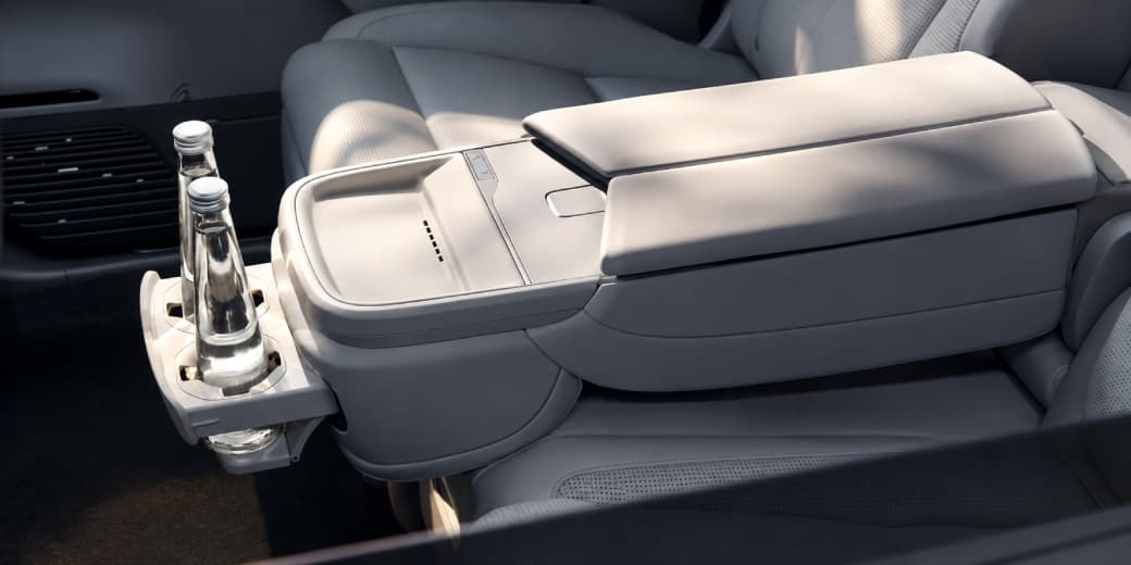 Folded Xpeng G9L rear centre armrest with two bottled drinks in its cup holder.