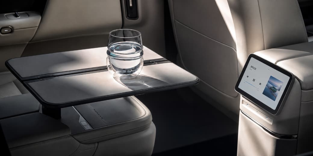Folding table, water glass and passenger screen inside the light-coloured Xpeng G9L interior.