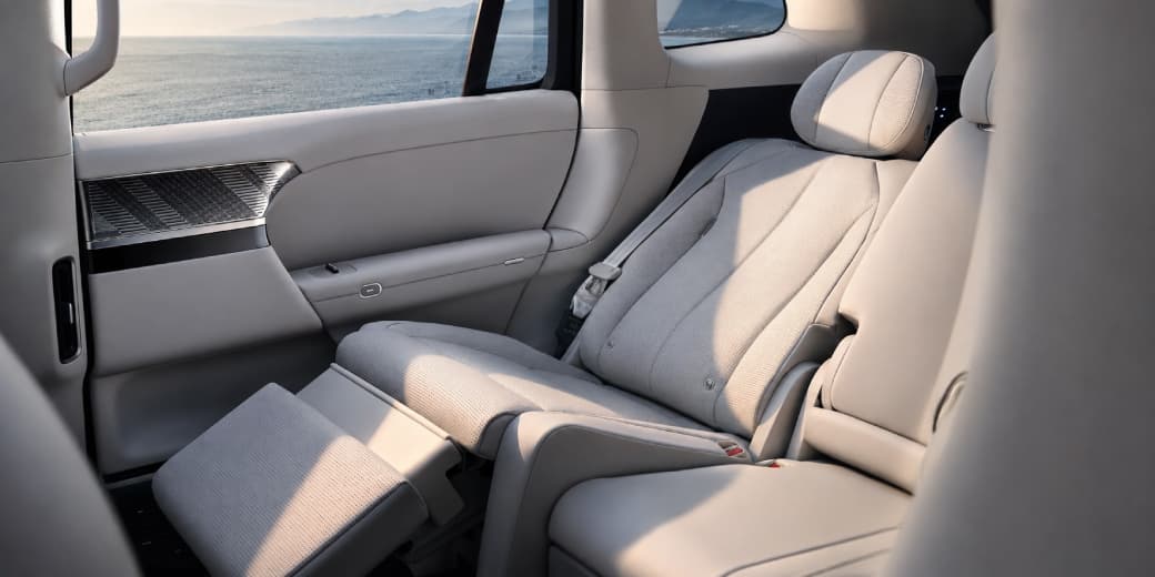 Light-coloured Xpeng G9L rear passenger seat reclined with its leg rest extended.