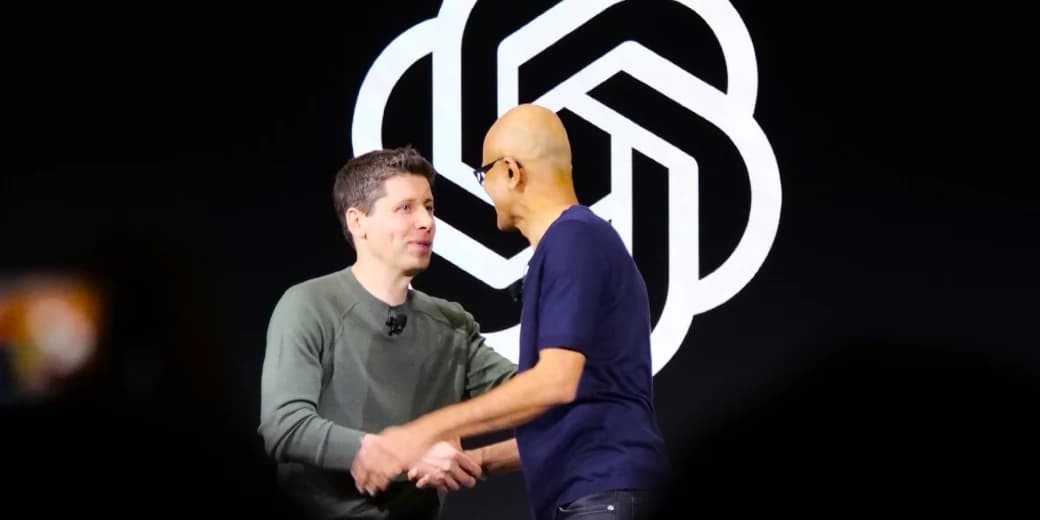 OpenAI chief executive Sam Altman greeting Microsoft chief executive Satya Nadella in front of the OpenAI logo.