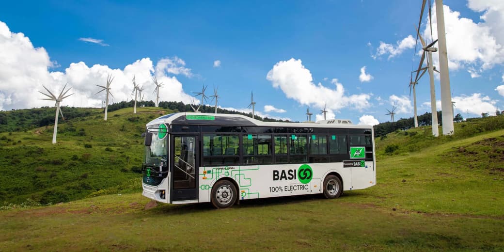 A BasiGo electric bus near wind power infrastructure. Credit: BasiGo.