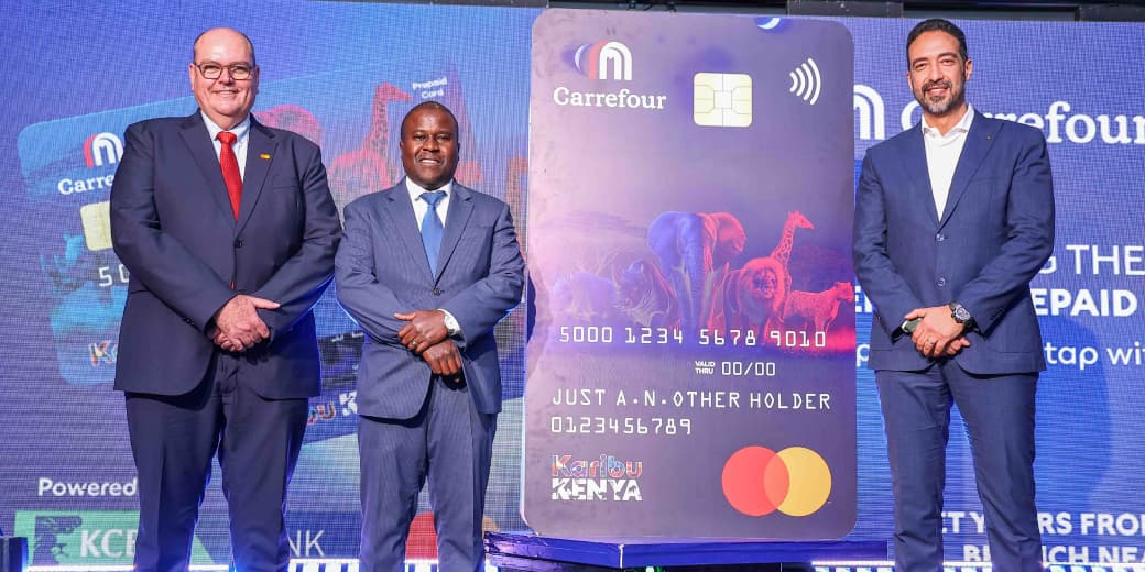 Three executives beside an oversized Carrefour Kenya prepaid Mastercard at its launch.