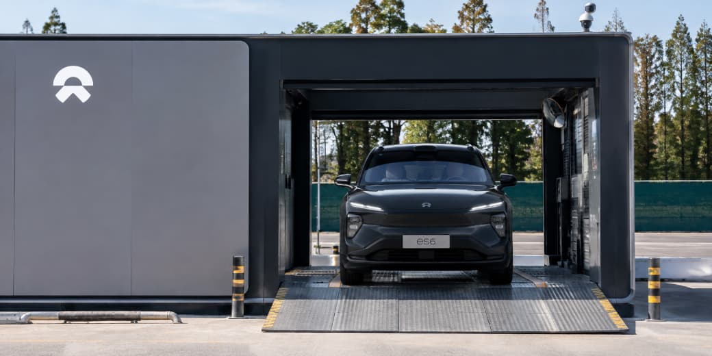 Dark grey Nio ES6 aligned at the entrance of a battery swapping station.