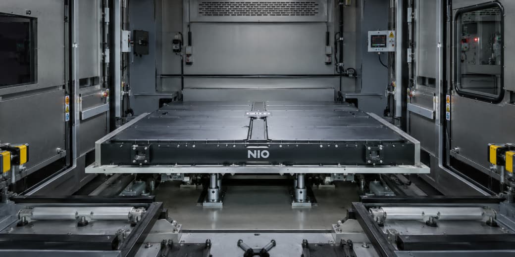 Interior of a Nio battery swapping station showing the automated battery handling platform and guide rails.