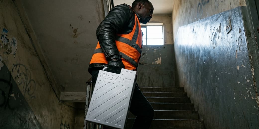 Boda-boda rider carrying a Roam Gen-3 battery up an apartment stairwell