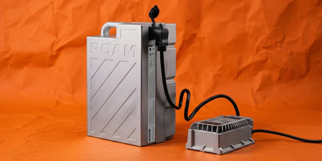 Roam Gen-3 battery and portable charger against an orange studio background