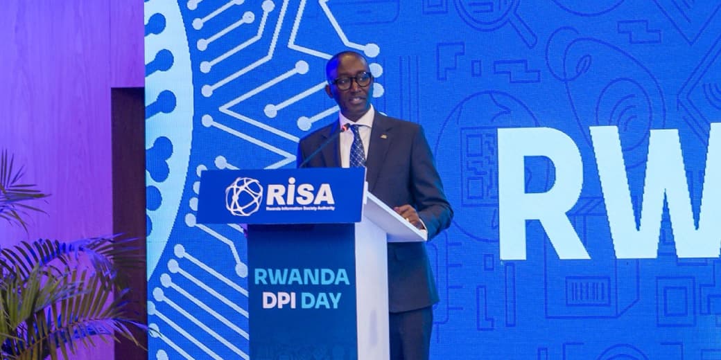 A speaker at Rwanda DPI Day in front of a Rwanda Information Society Authority backdrop. Credit: AFRwanda / x.com.