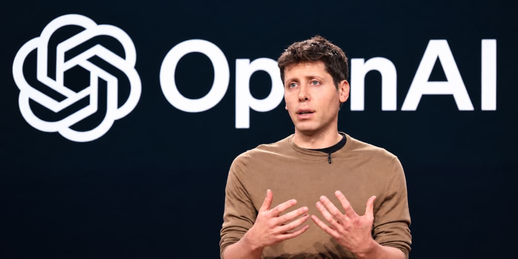 OpenAI CEO Sam Altman speaking in front of the OpenAI logo.