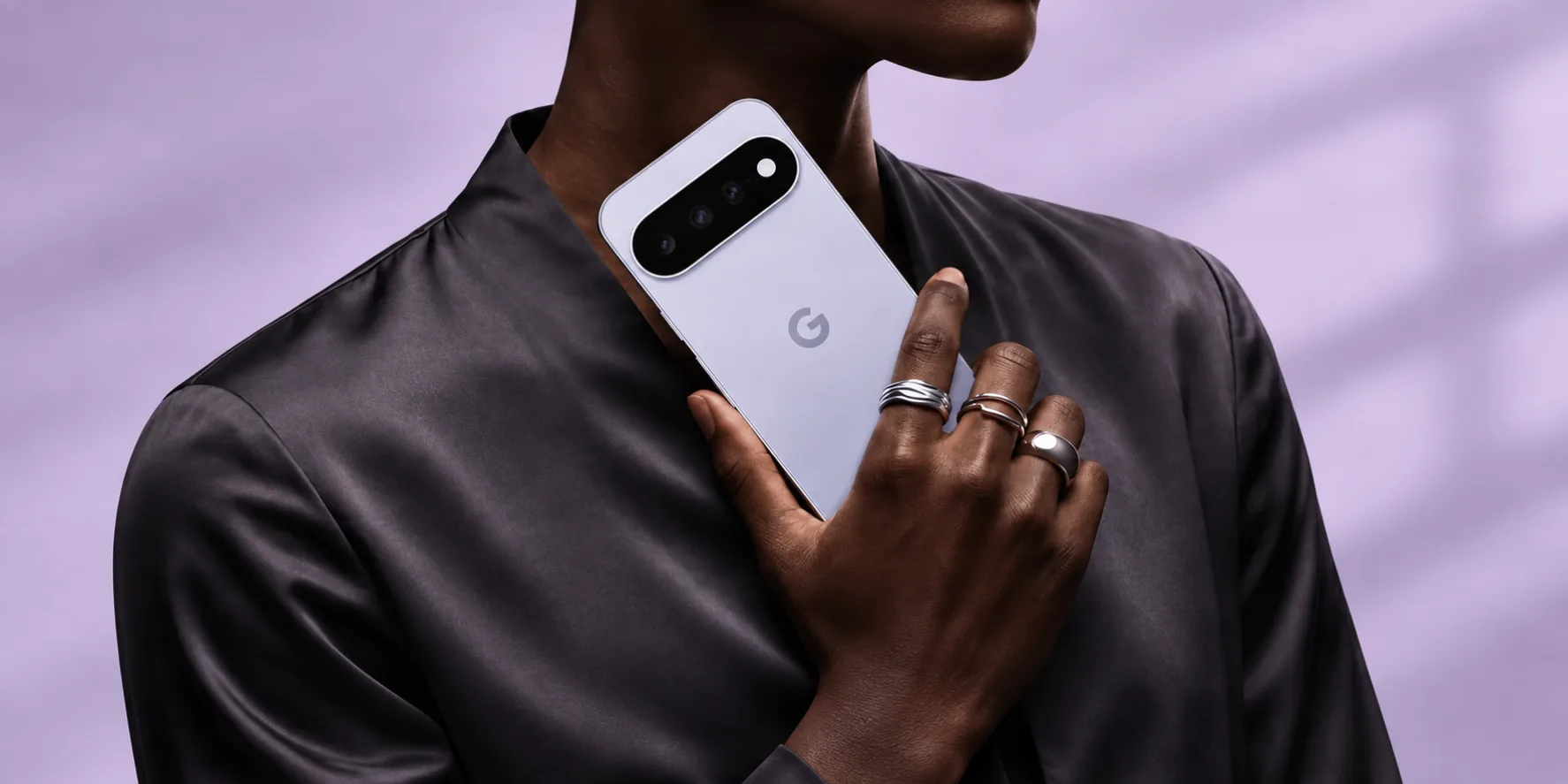 A person holding a pale purple Google Pixel phone against a matching lavender background.