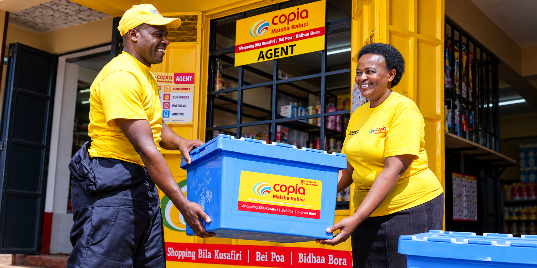 Two Copia Kenya agents carrying a blue delivery container outside a branded shop.